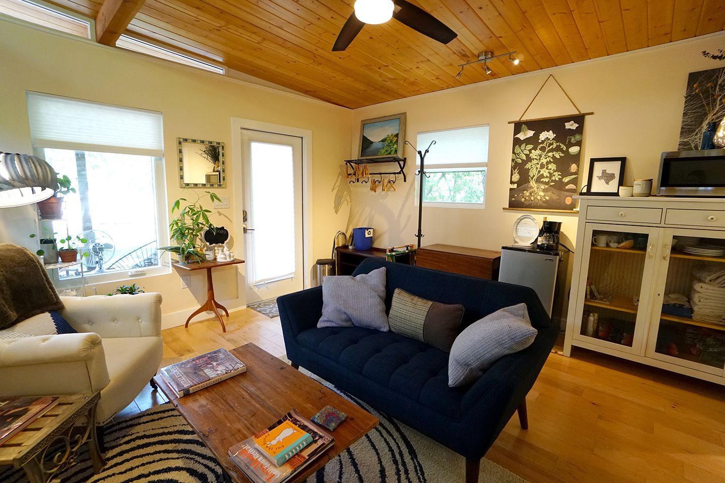 Cozy living room with blue sofa, wooden coffee table, and light-colored walls and ceiling; natural light.