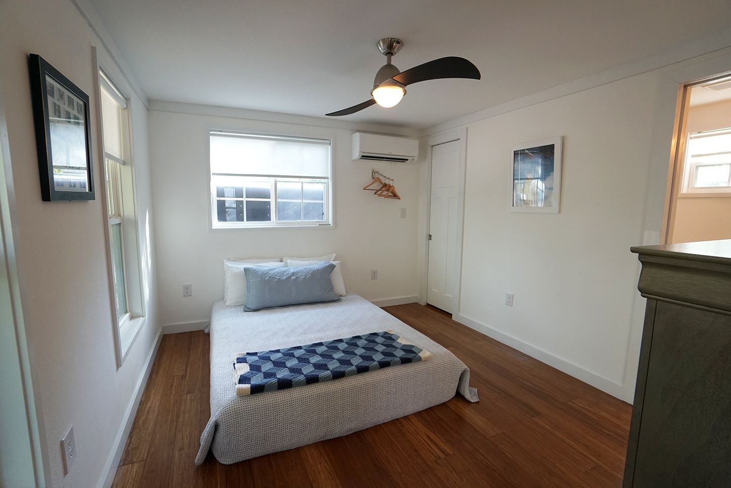 Bedroom with bed, hardwood floors, window, and ceiling fan.