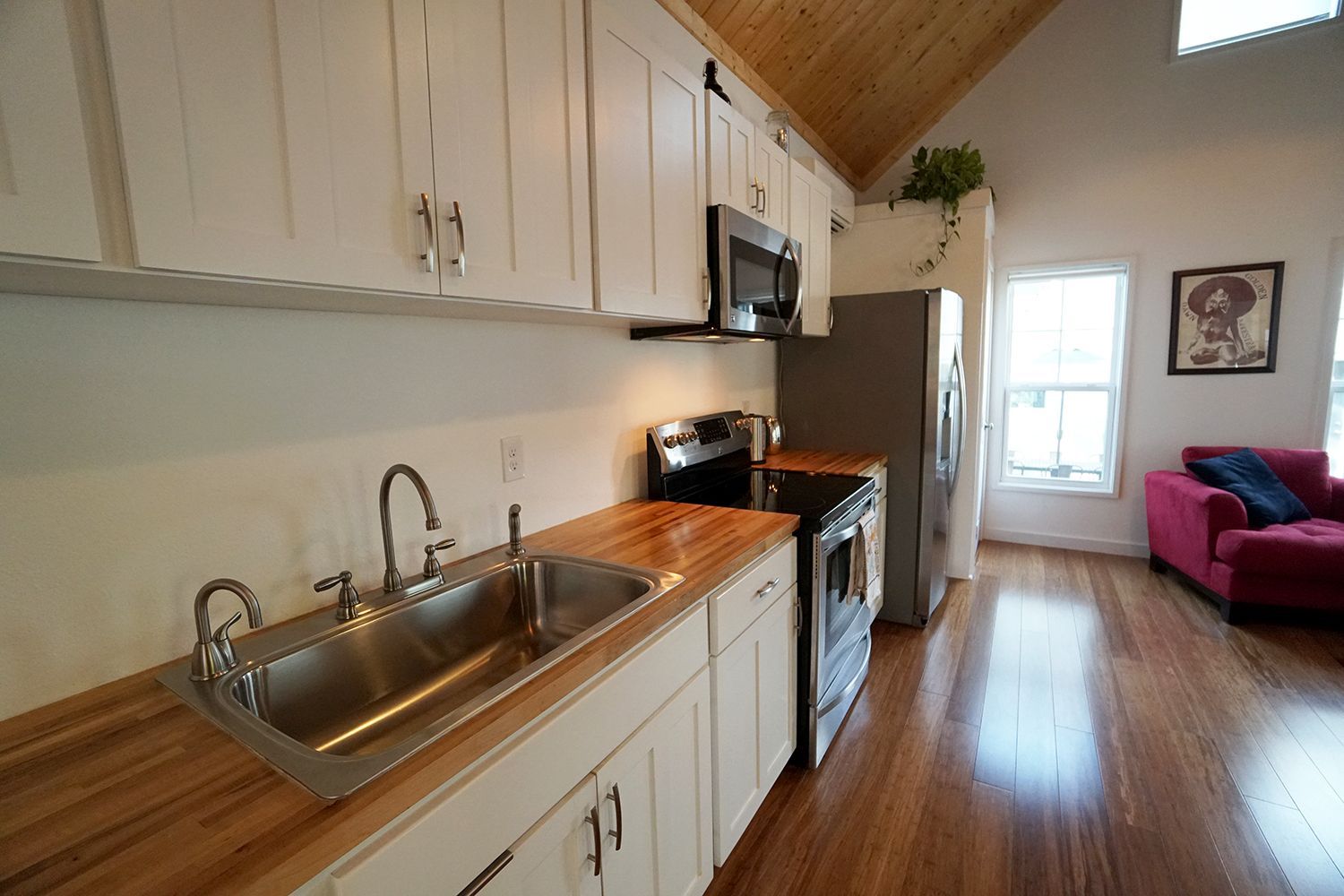 Kitchen with white cabinets, stainless steel sink, wooden countertops, and hardwood floor.