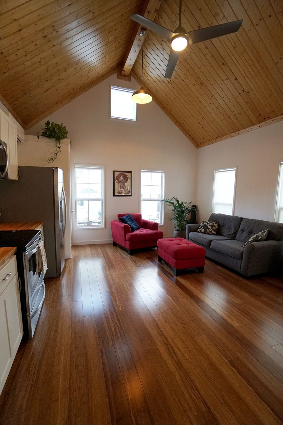 Living room with wood floors, vaulted wood ceiling, red furniture, and a gray sofa.