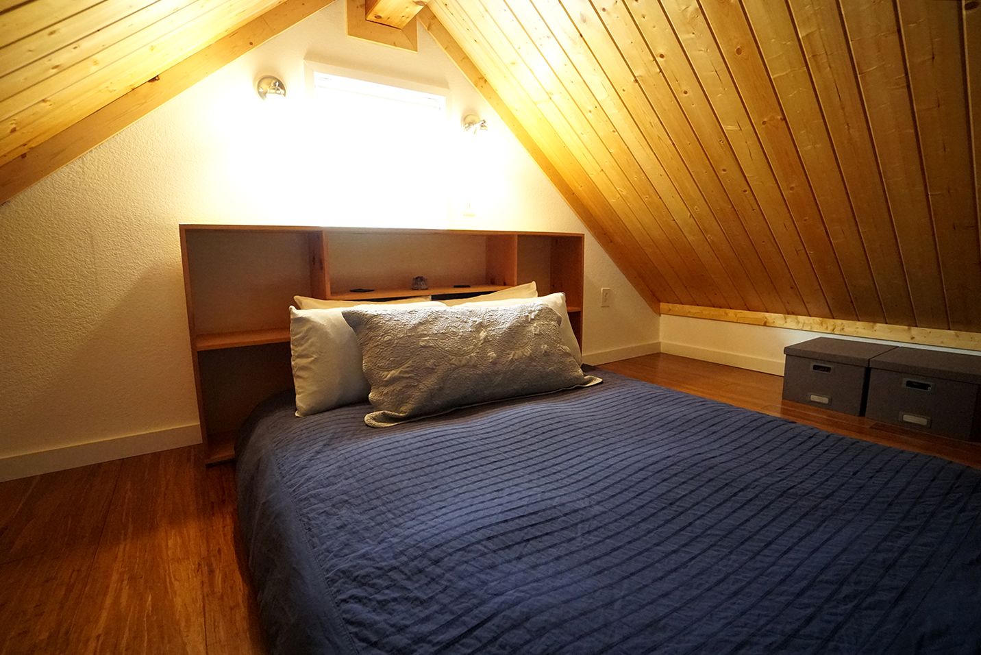 Bedroom in an attic with a bed, wood paneling, and a headboard.