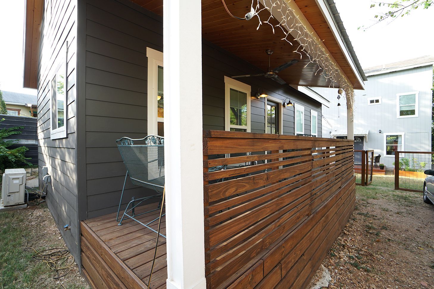 Exterior of a modern dark gray house with a wooden slatted privacy fence.