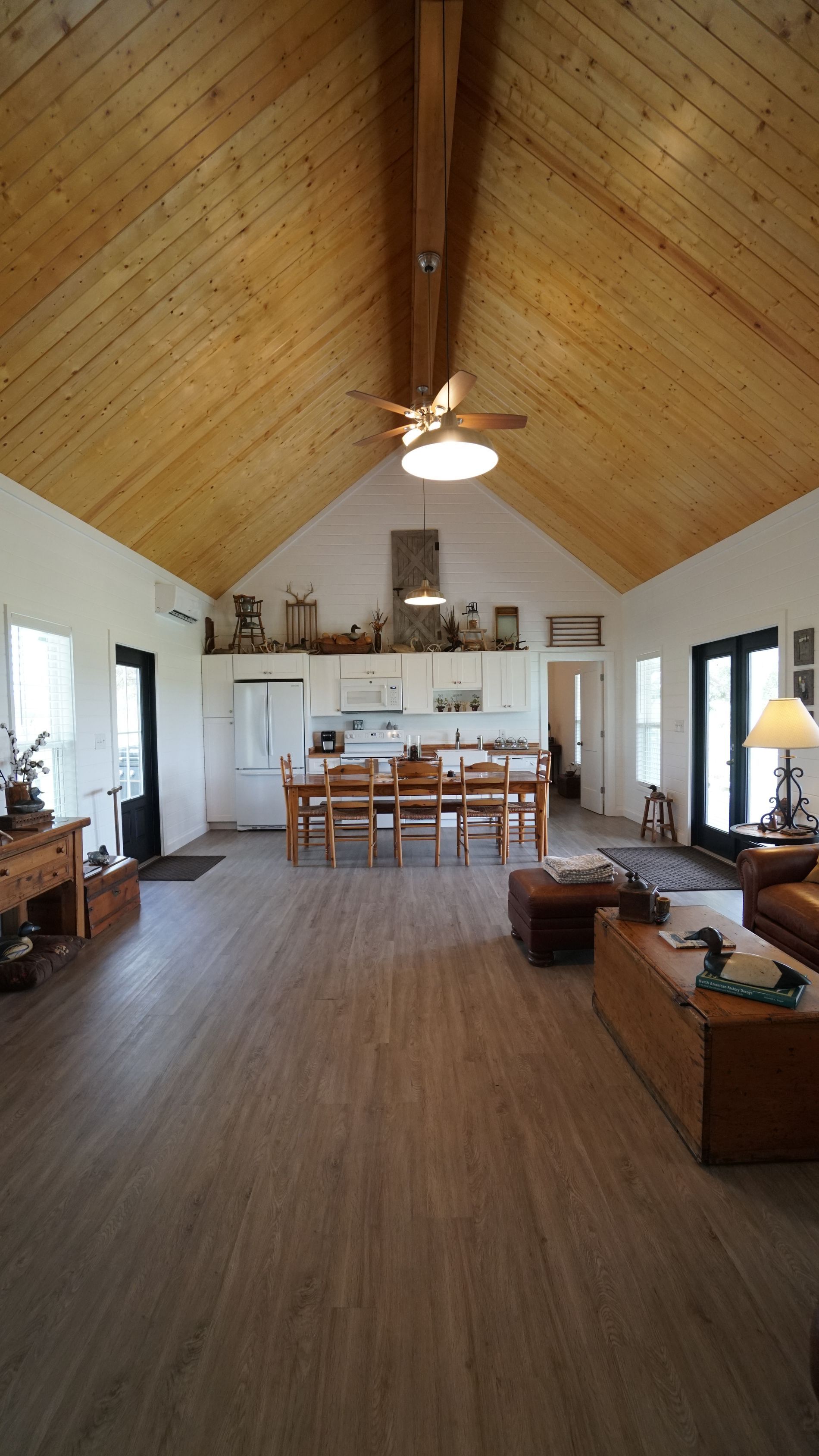 Spacious interior with wooden ceiling and floor, dining area with table, and living room with couches.