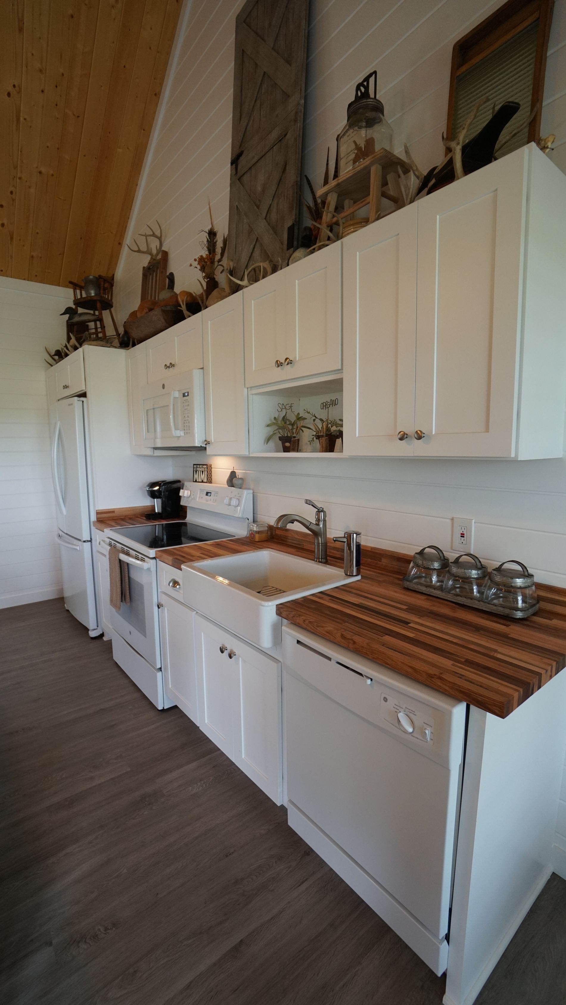 White kitchen with wooden countertops, white cabinets, and a white sink.