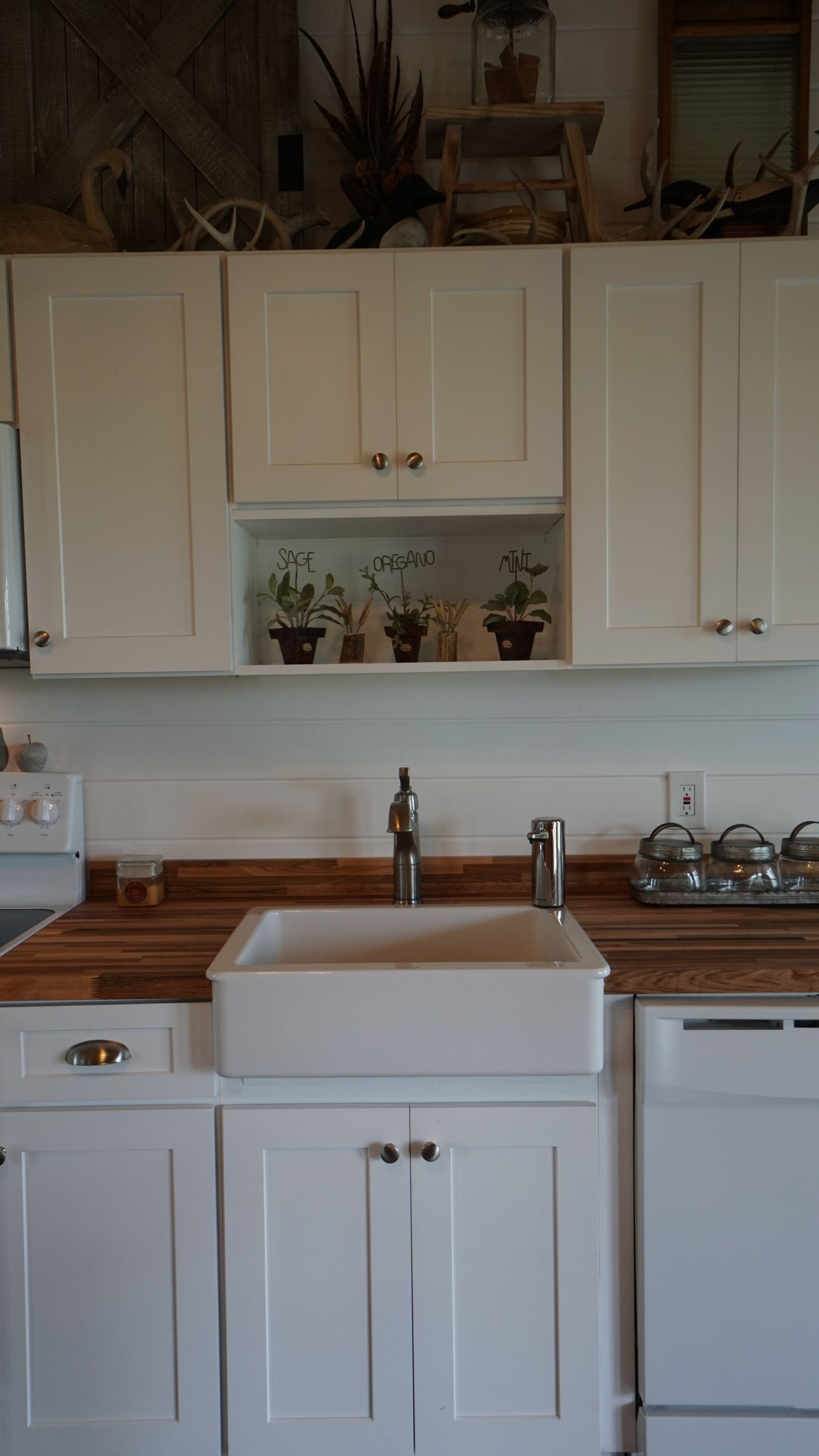 White kitchen with wood countertops, white cabinets, and a white farmhouse sink.