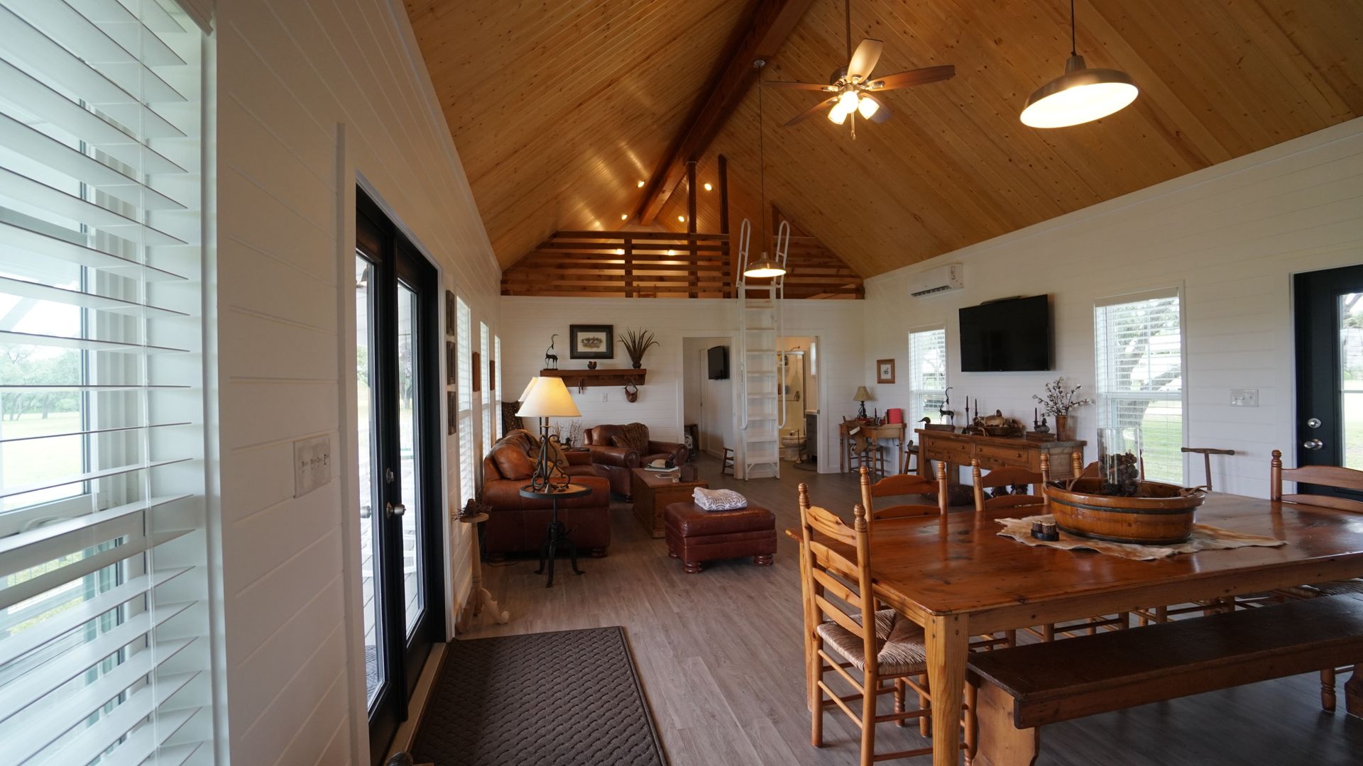 Spacious living room with wood ceiling, dining table, and large windows.