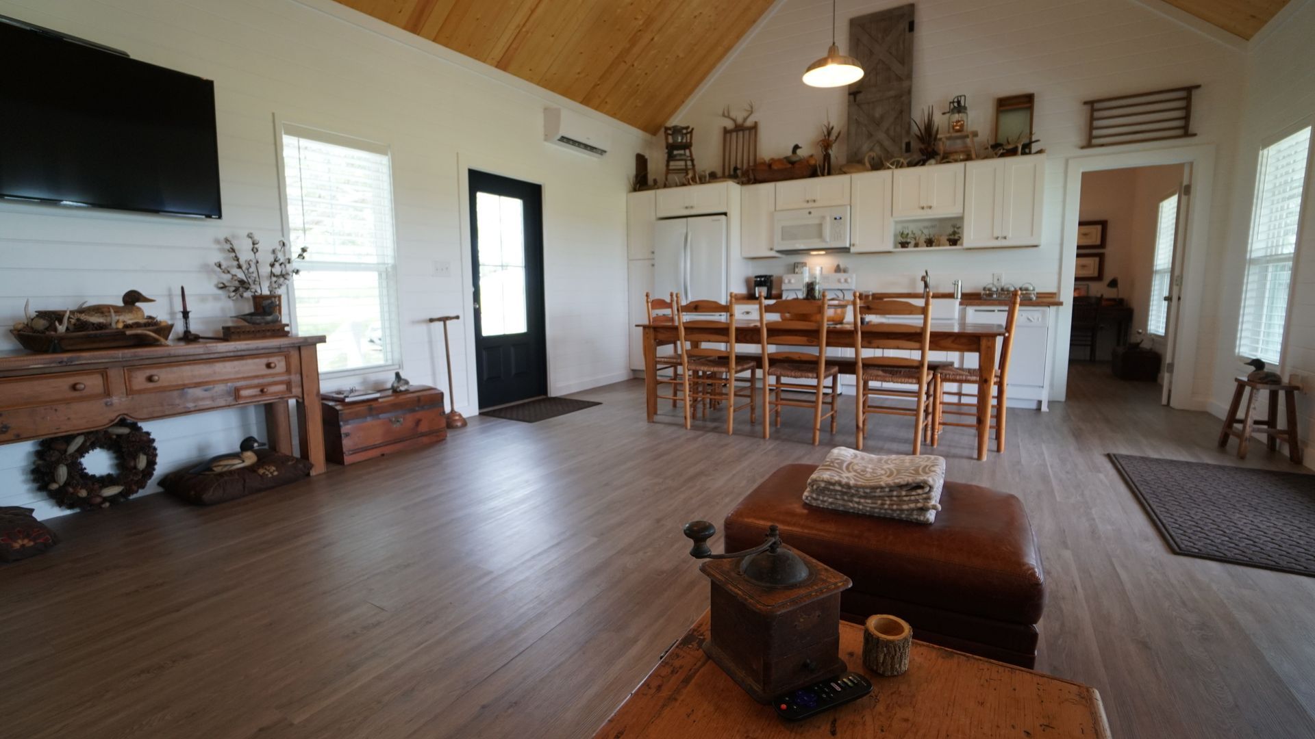 Spacious interior with white walls, wood floors, and kitchen with dining table. Decorative items and furniture throughout.