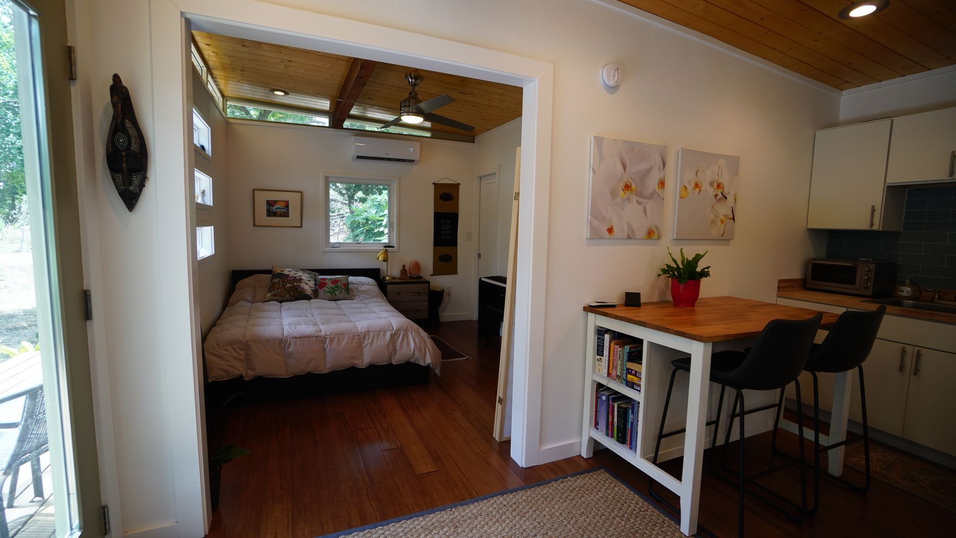 Cozy small home interior with bed, kitchen, and dining area visible through archway.