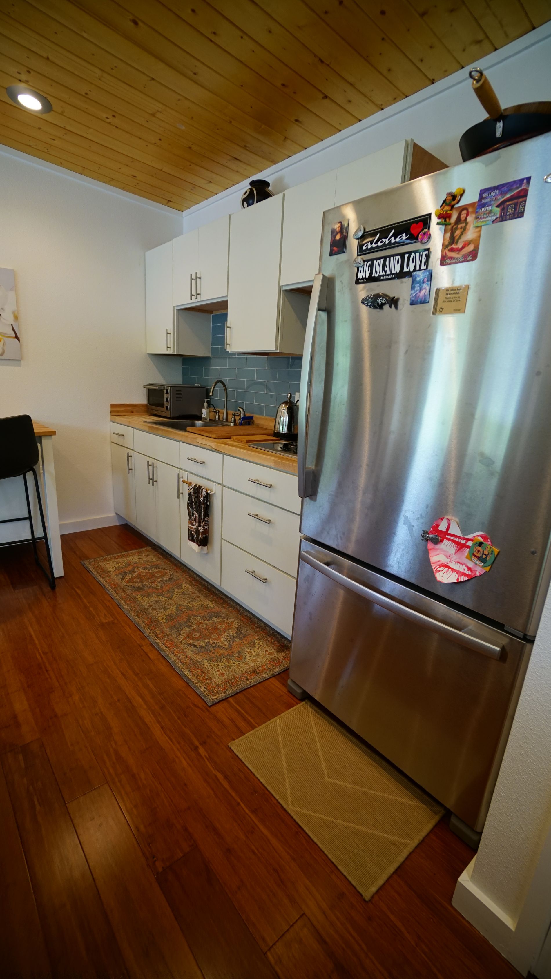 Kitchen with white cabinets, stainless steel refrigerator, and wood floor.