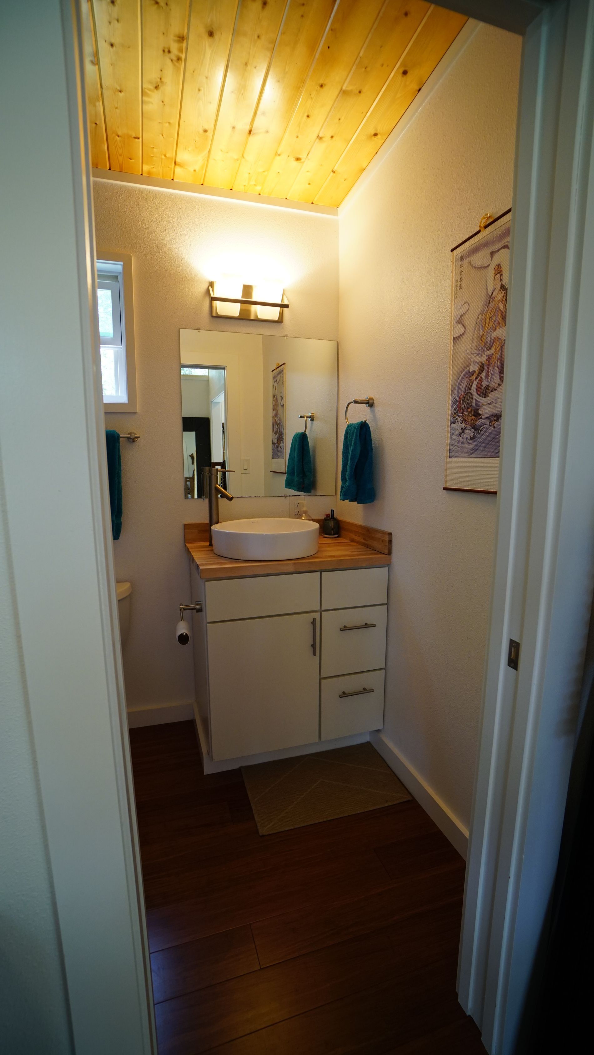 Small bathroom with white vanity, wood ceiling, and round sink.
