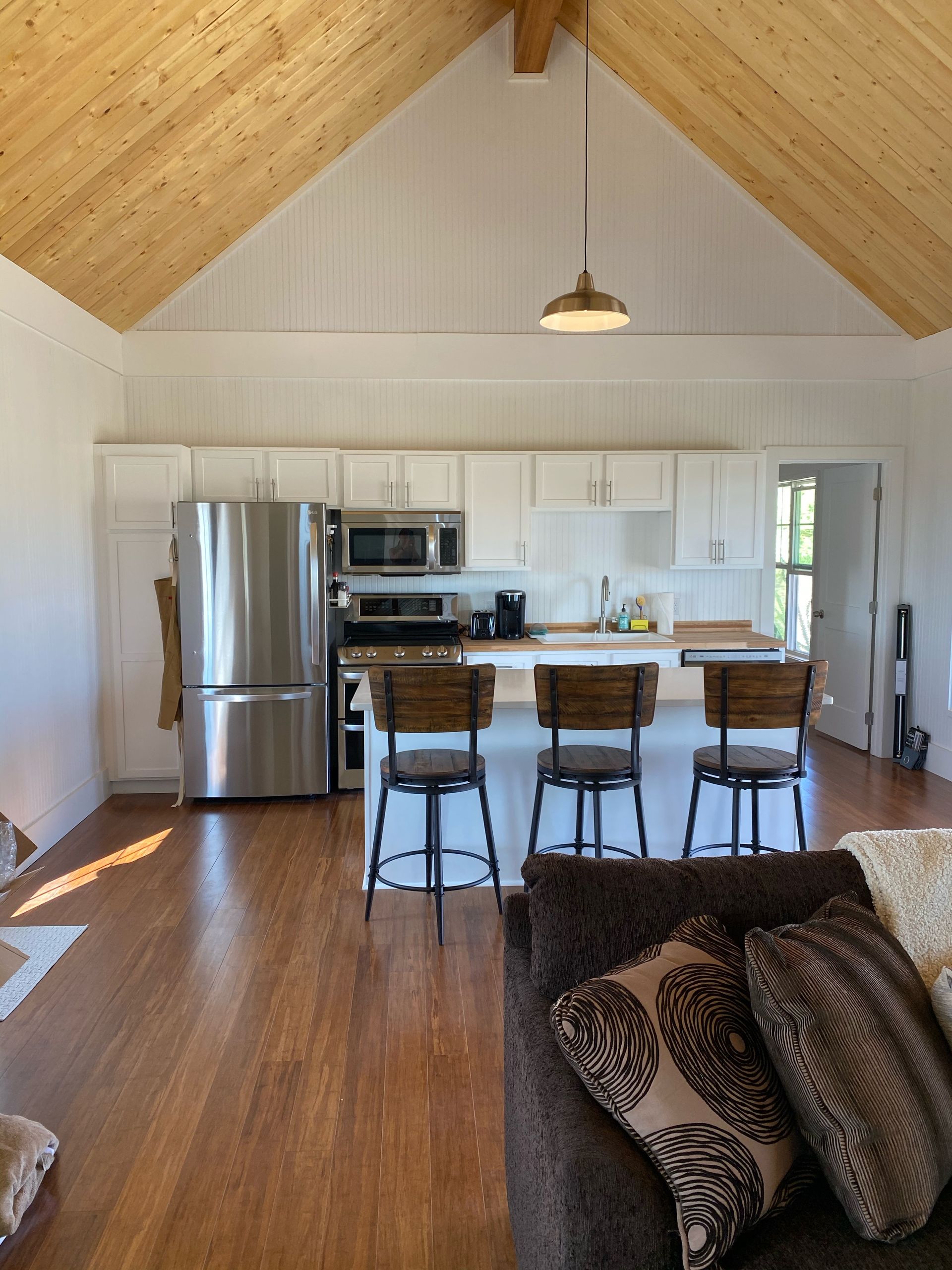 Kitchen with wood ceiling, white cabinets, stainless steel appliances, and wood floors.
