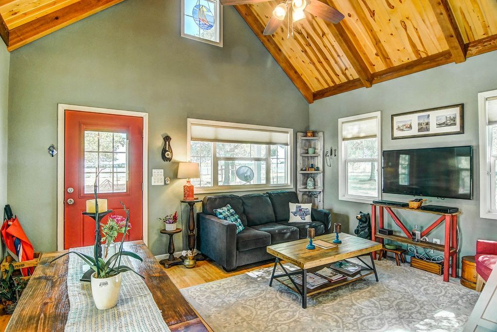 Cozy living room with gray walls, wooden ceiling, red door, and a small sofa.