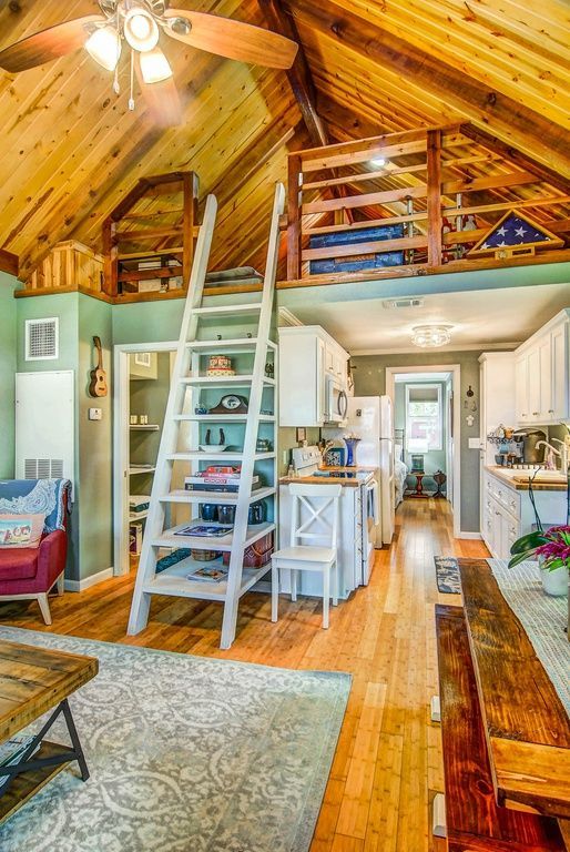 Cozy interior with a loft, ladder, wooden ceiling, and kitchen.