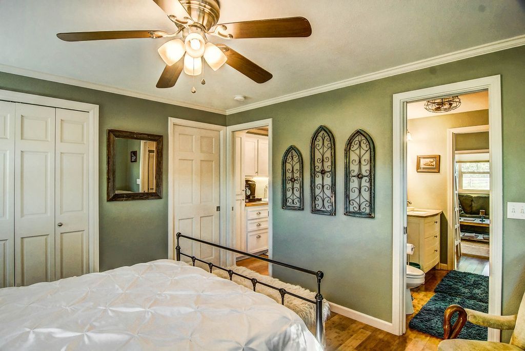 Bedroom with a bed, closet, and doorway to a bathroom. Green walls, white trim, and a ceiling fan.