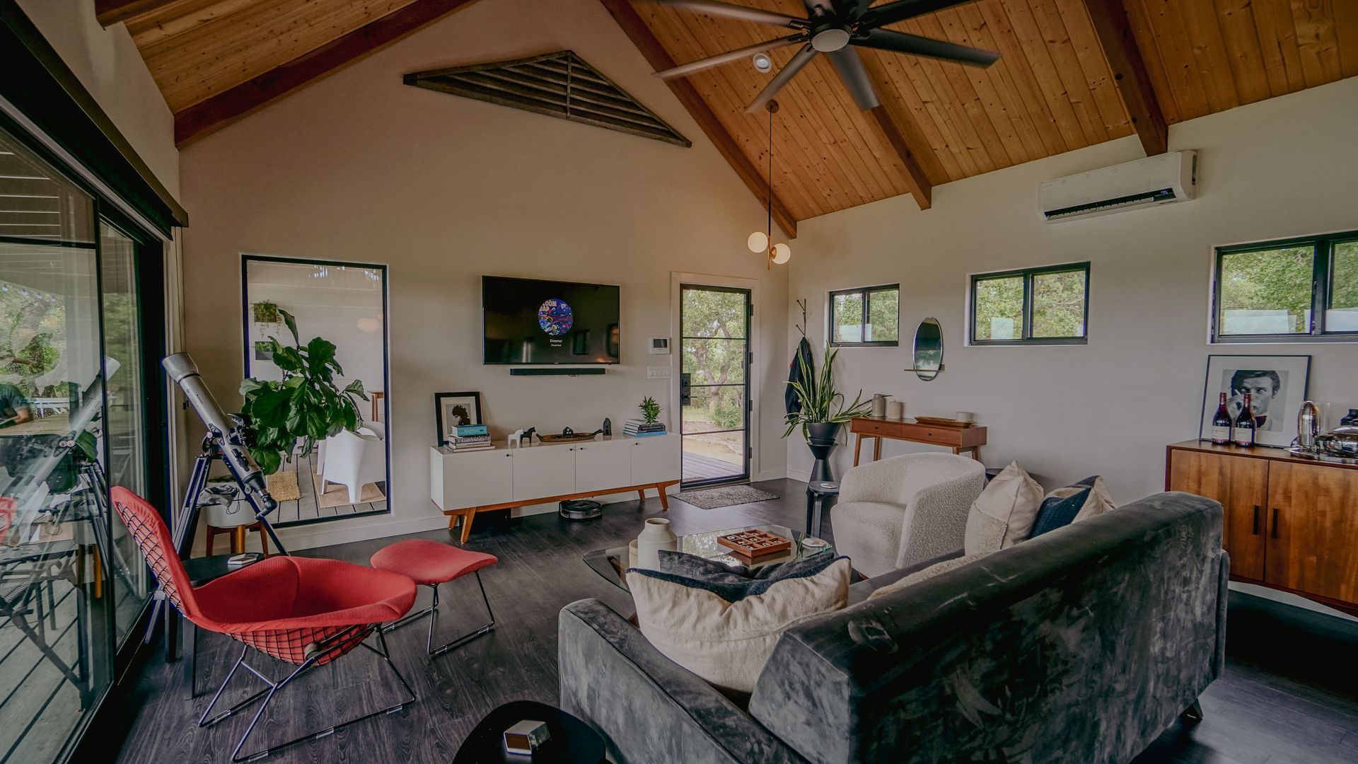 Living room with high wood ceiling, glass doors, and modern furniture.