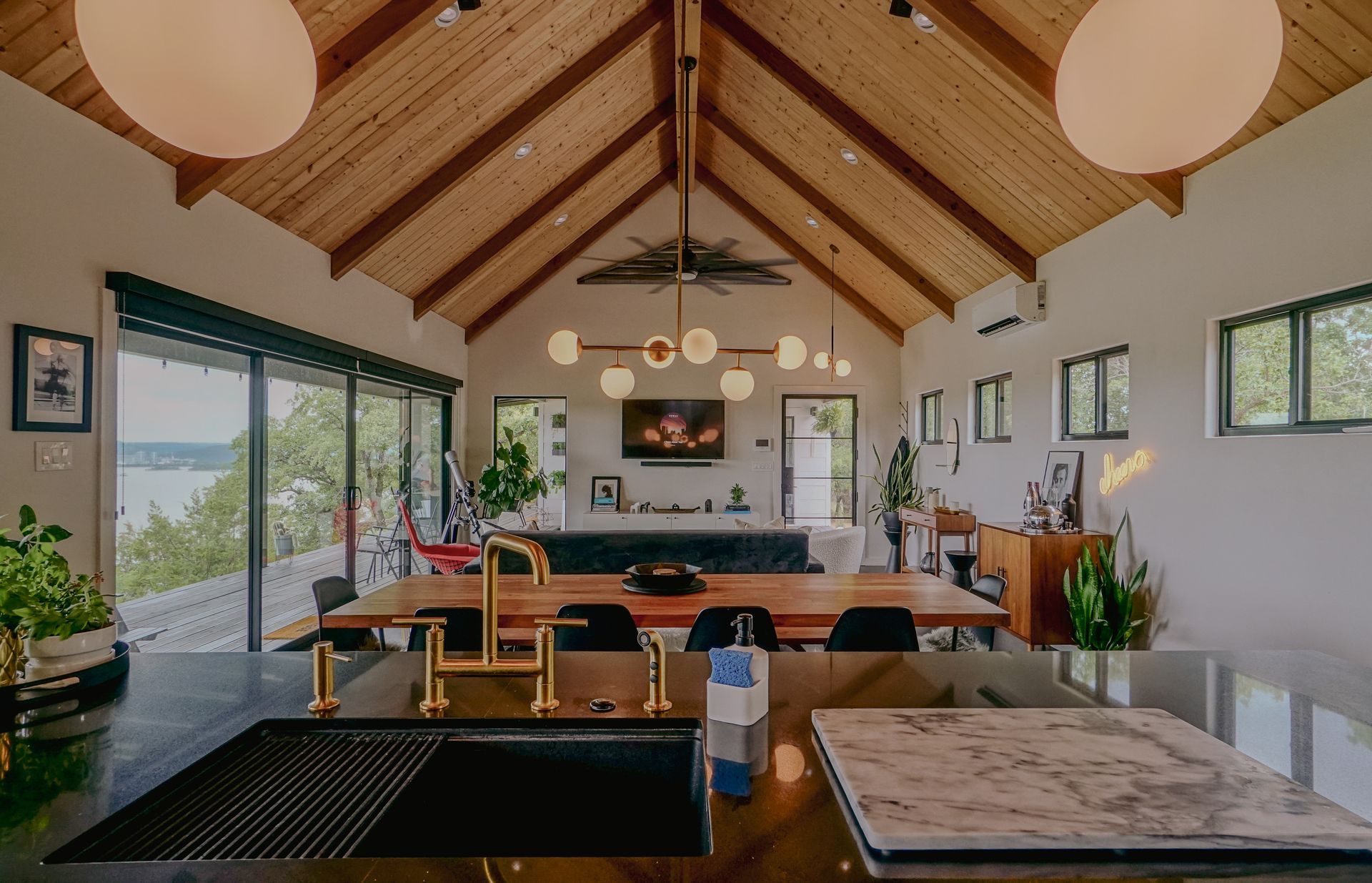 Modern home interior with vaulted wood ceiling, open plan with dining table, and kitchen island.