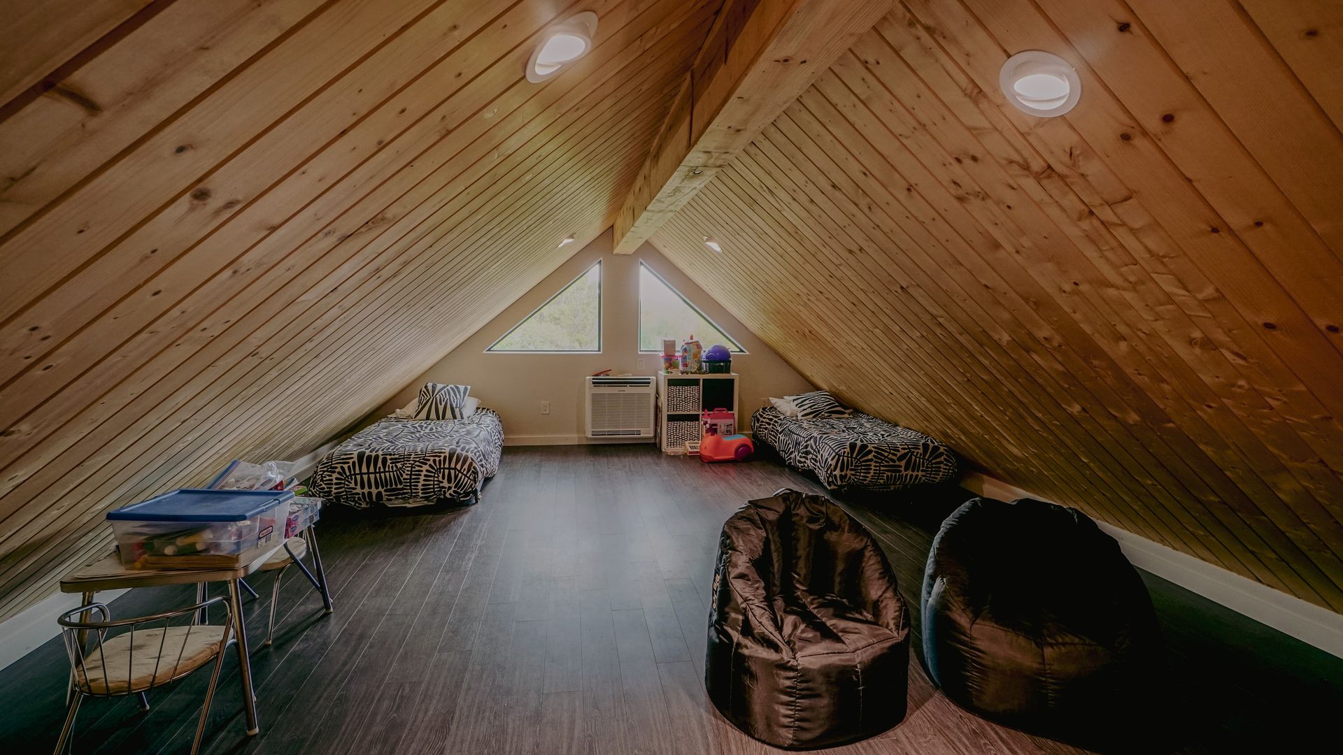 Attic room with wood paneling, bean bag chairs, and child's bed.