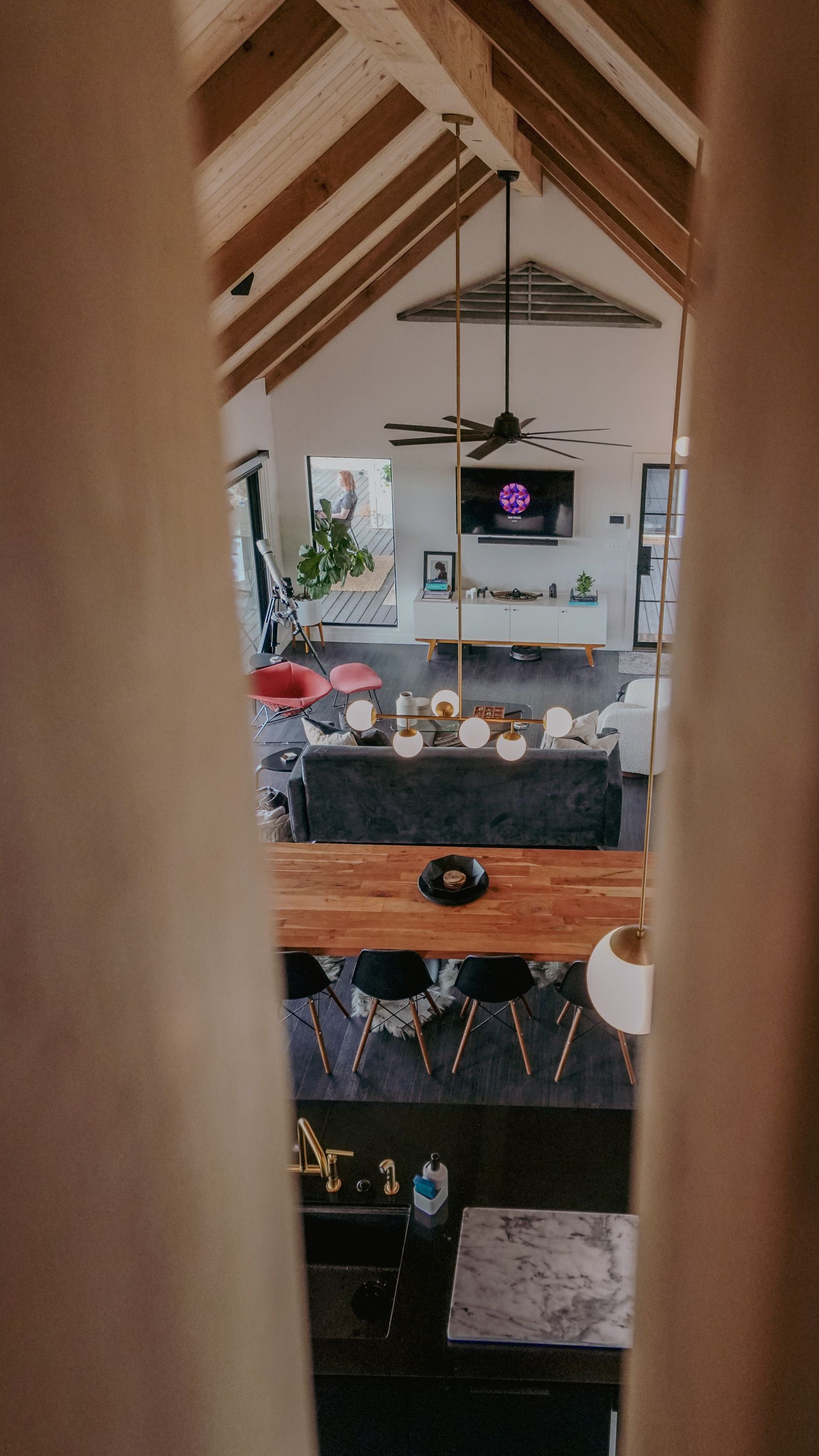 Interior view of a modern home with vaulted ceiling, kitchen island, living room, and a TV.