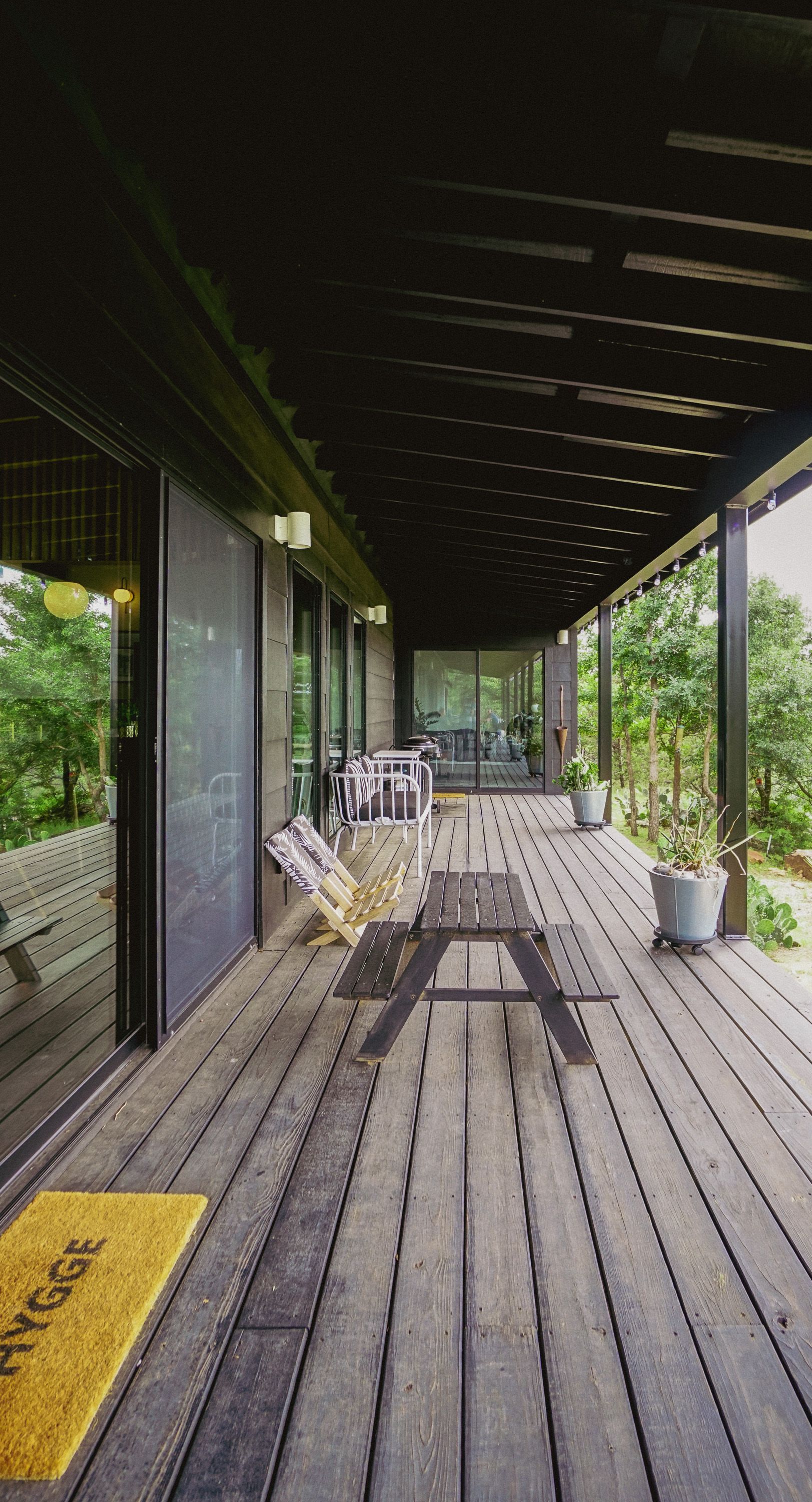 Wooden deck with a covered roof. Sliding glass doors and patio furniture. Yellow welcome mat.