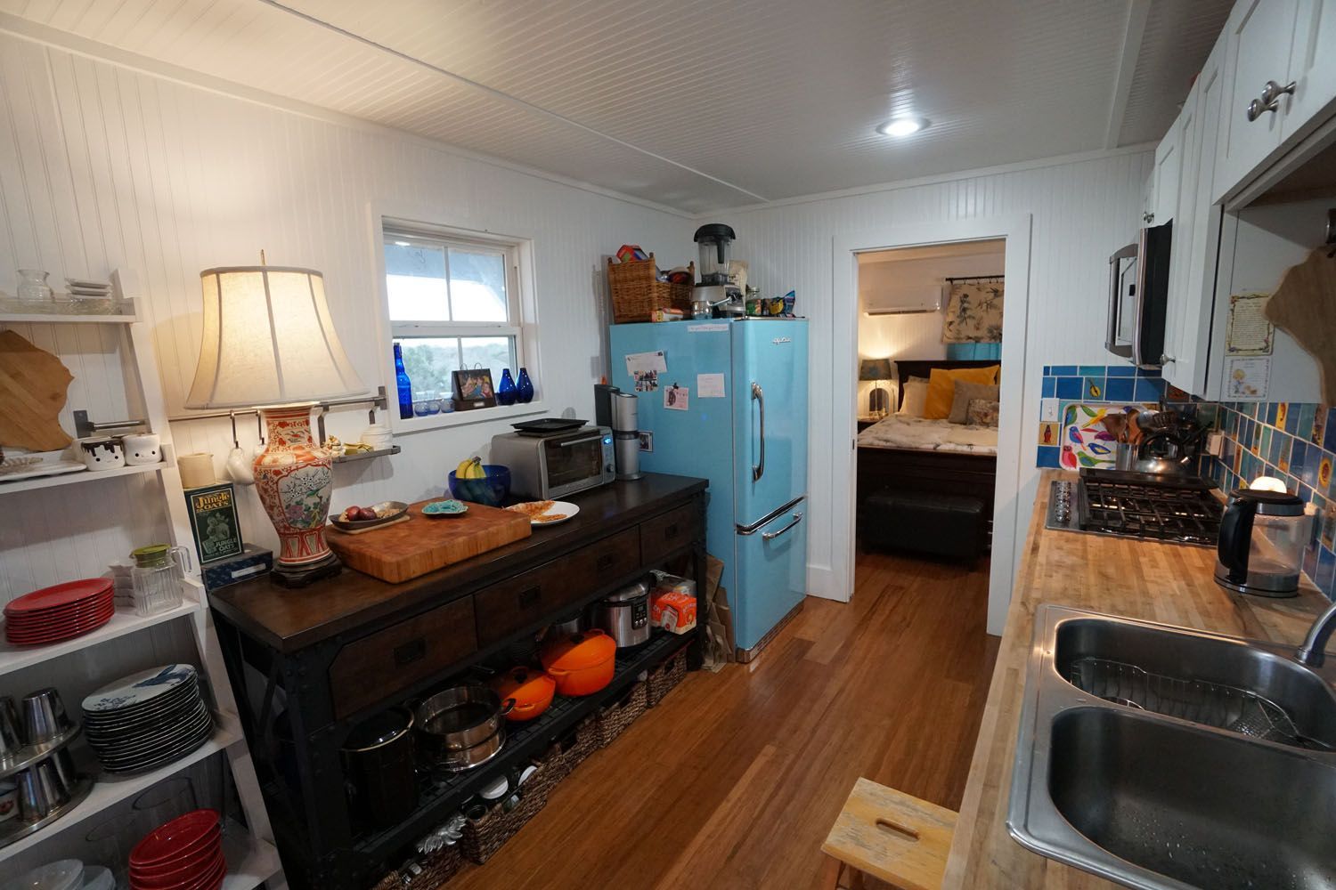 Cozy kitchen interior with vintage decor, retro blue fridge, and a glimpse of a bedroom.