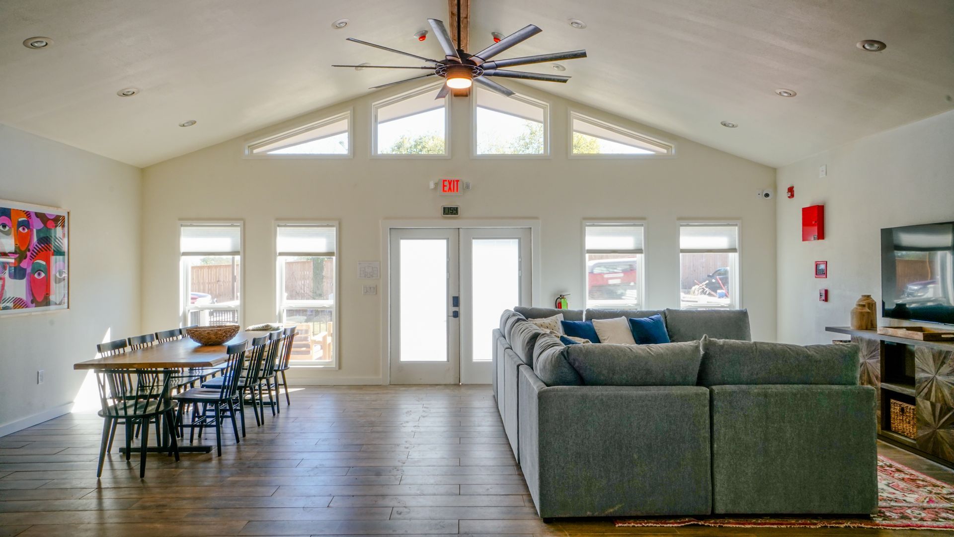 Spacious room with large sectional sofa, dining table, and large windows. Ceiling fan.