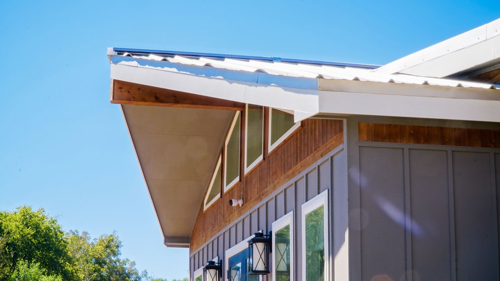 Exterior view of a house with a slanted roof, windows, and siding under a clear blue sky.