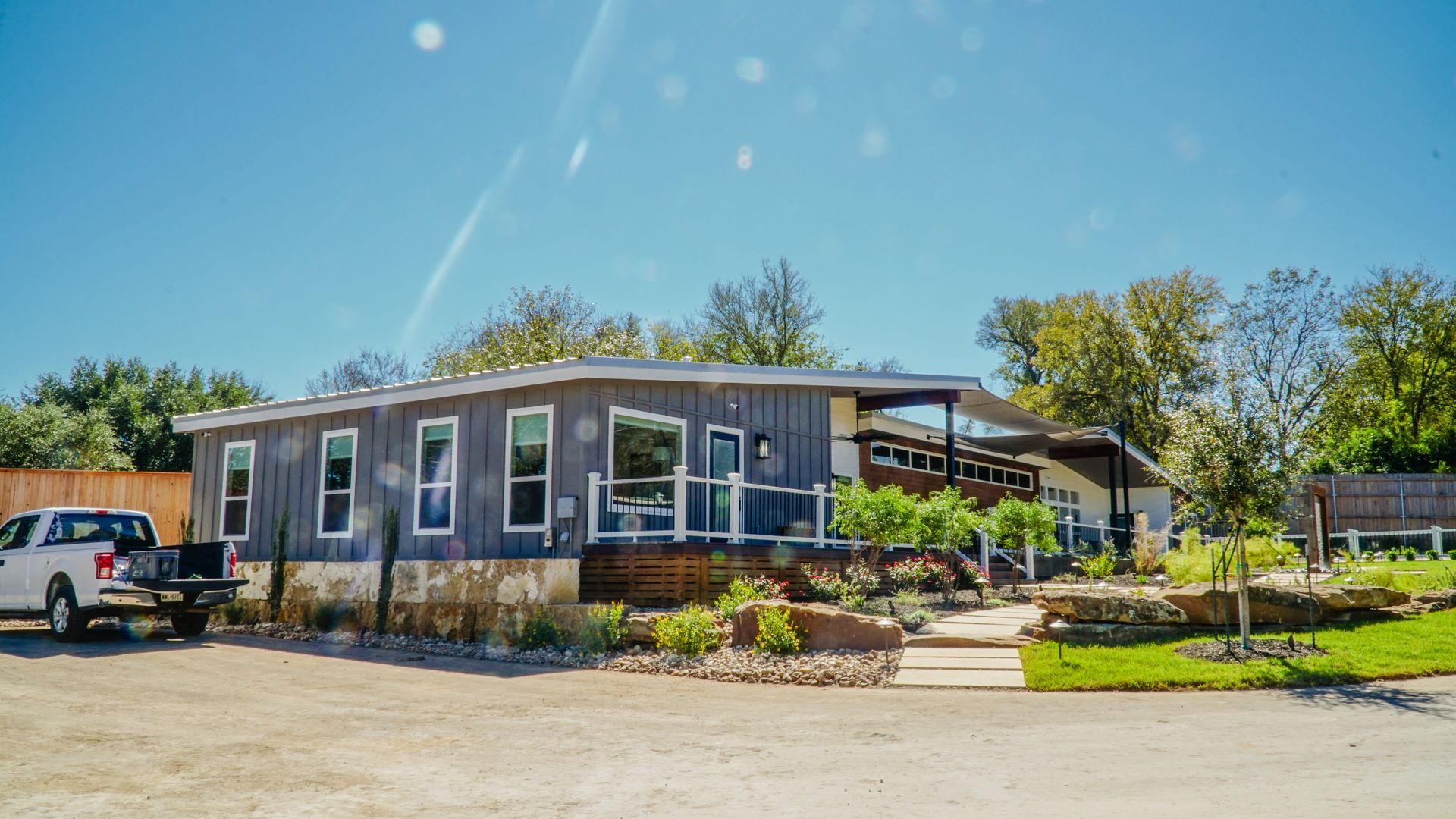 A single-story building with a covered porch and stone facade. A white pickup truck is parked beside it.