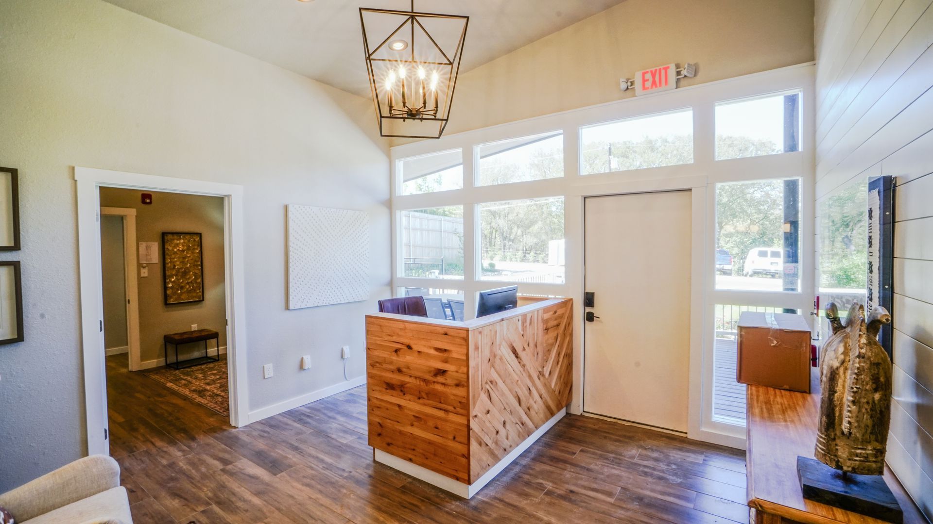 Reception area with wooden desk, large windows, and an open doorway.