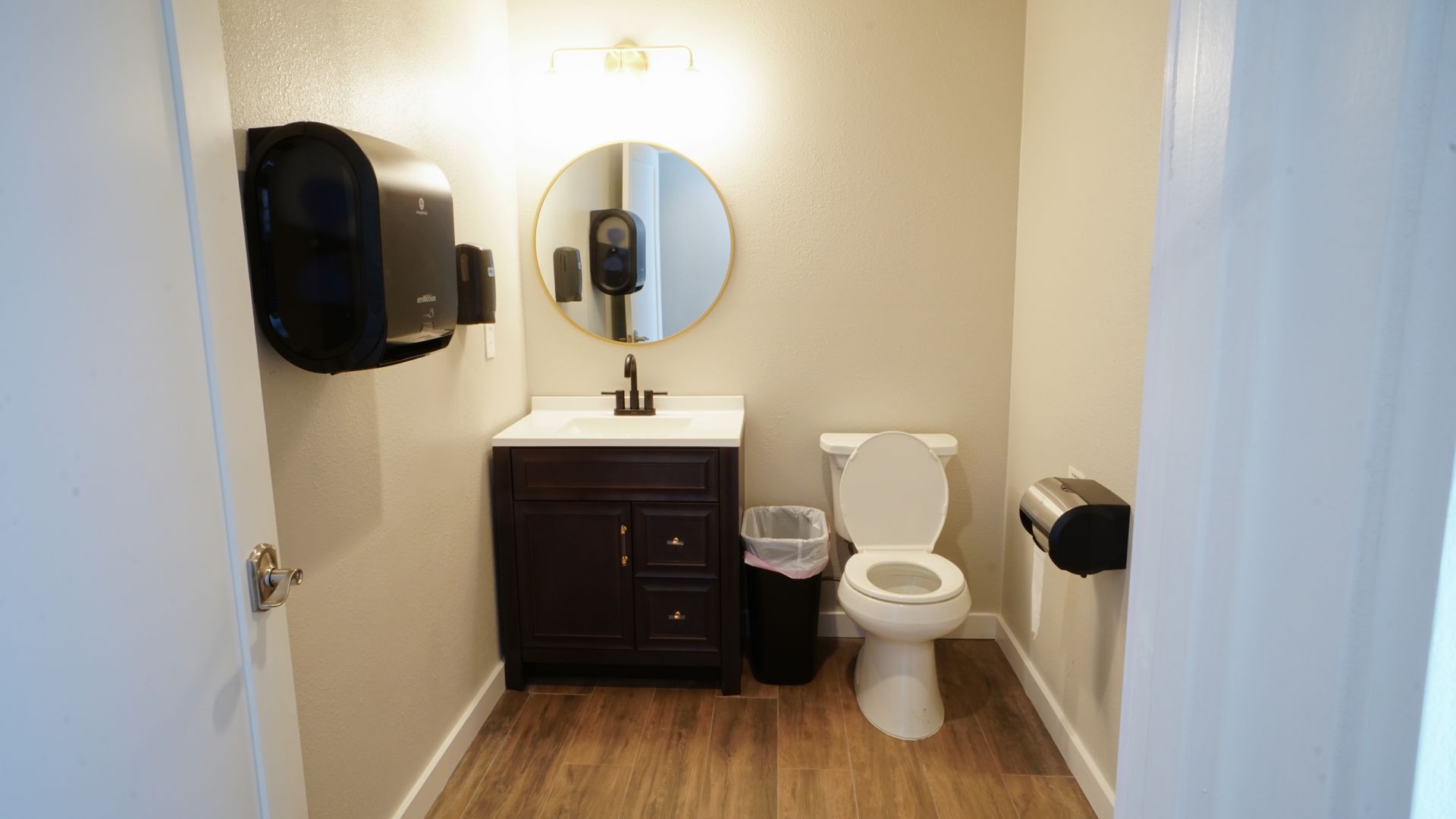 Small restroom with a sink, toilet, and paper towel dispenser.