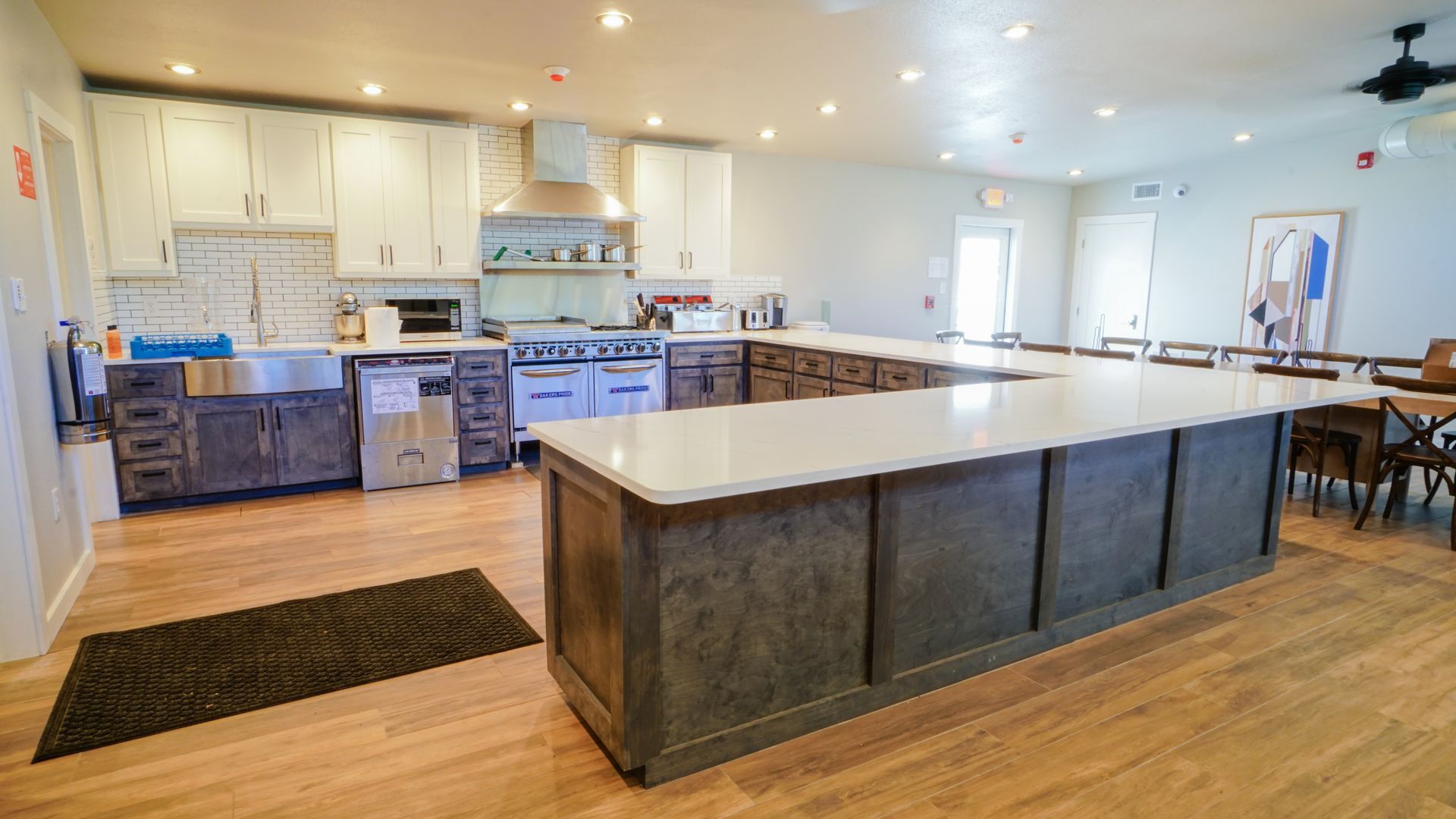 Large, open kitchen with U-shaped island, stainless steel appliances, light wood cabinets, and light wood flooring.