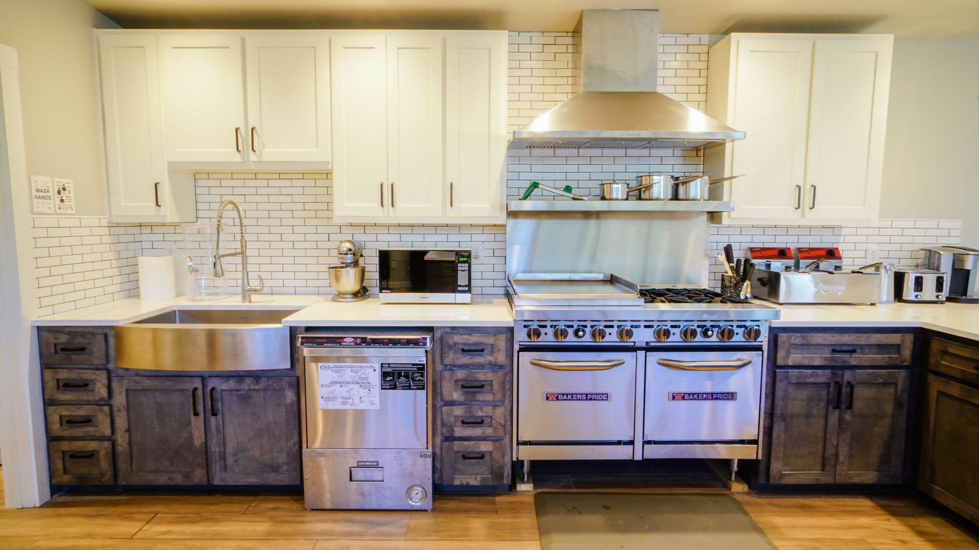 Kitchen with stainless steel appliances, white and gray cabinets, and a brick backsplash.