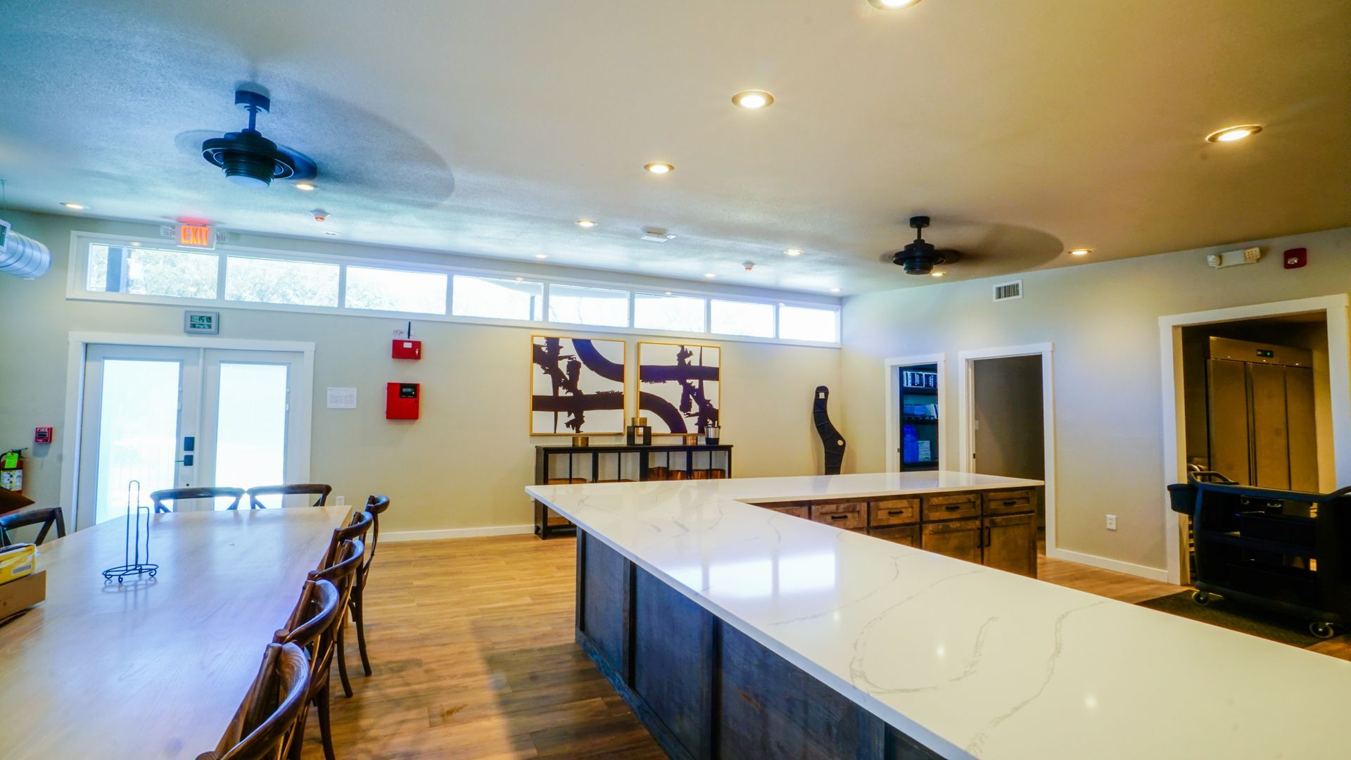 Spacious kitchen/dining area with long counter, tables, and artwork on the wall.