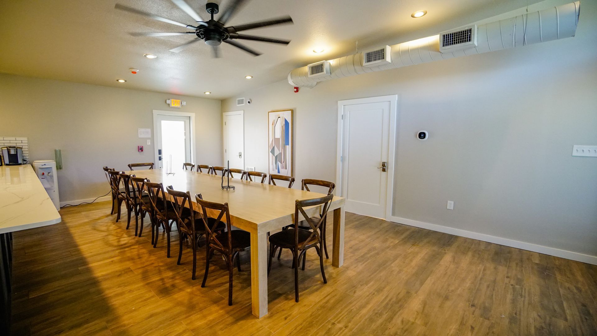 Large room with long table and chairs; a ceiling fan.