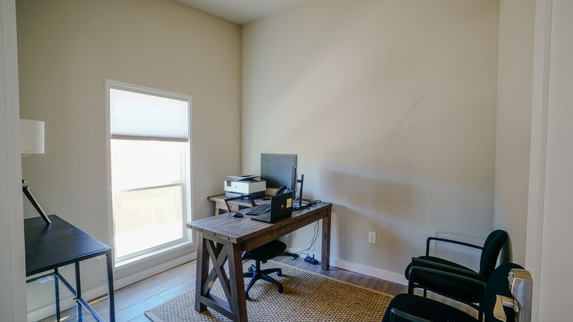 Office space with desk, computer, printer, chair, window, and rug.