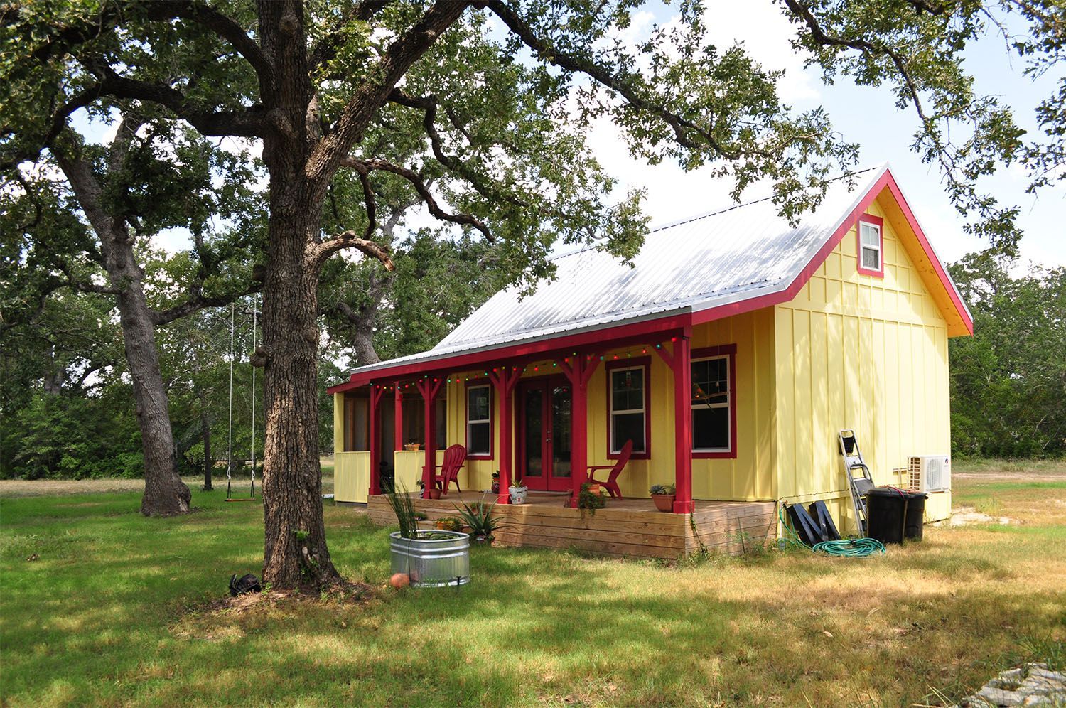 A small yellow house with red trim and a porch