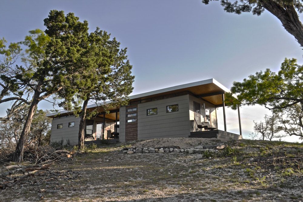 A small house is sitting on top of a hill surrounded by trees.