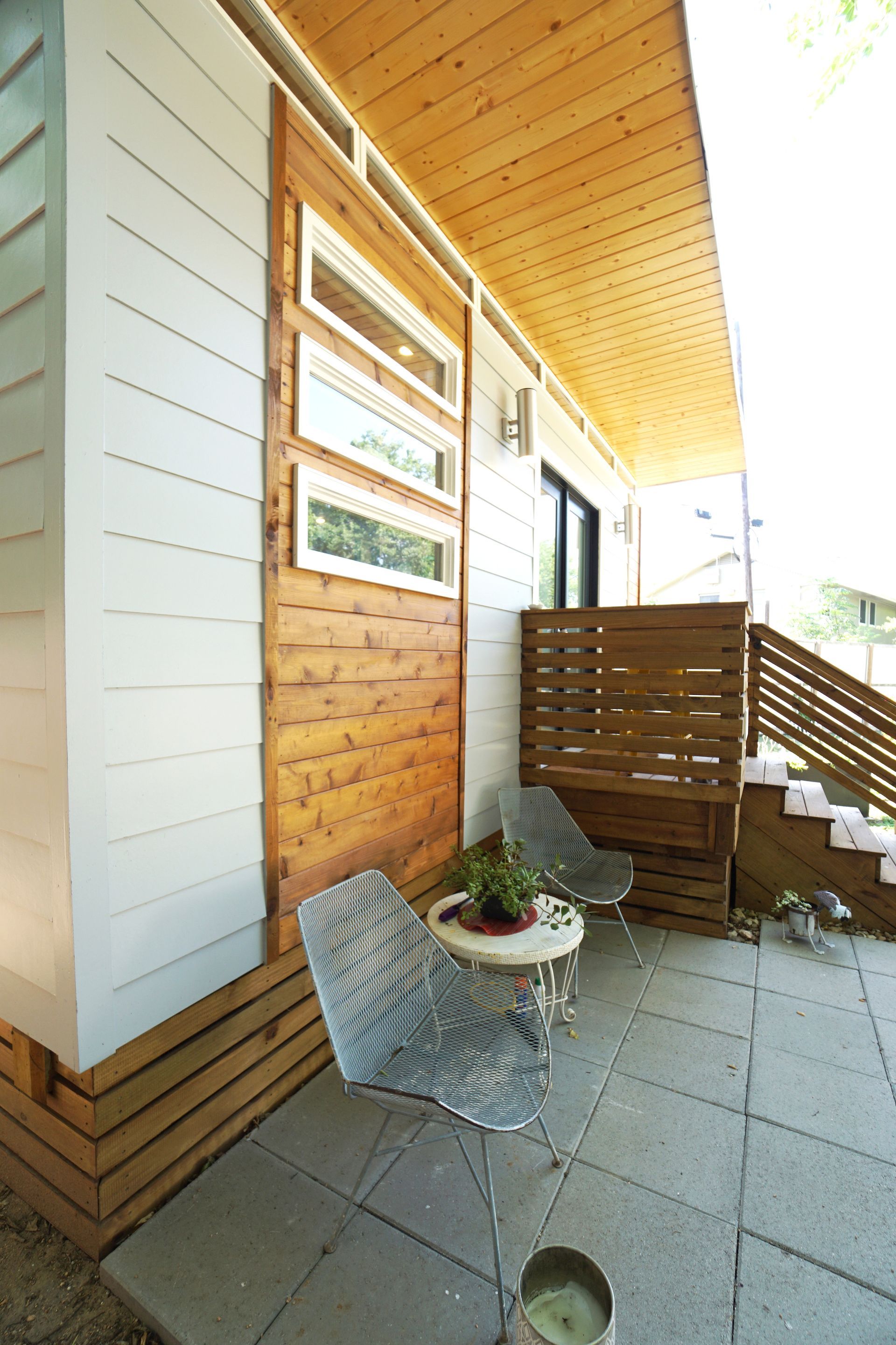 Exterior patio with two chairs, small table, and a wooden door with glass windows.