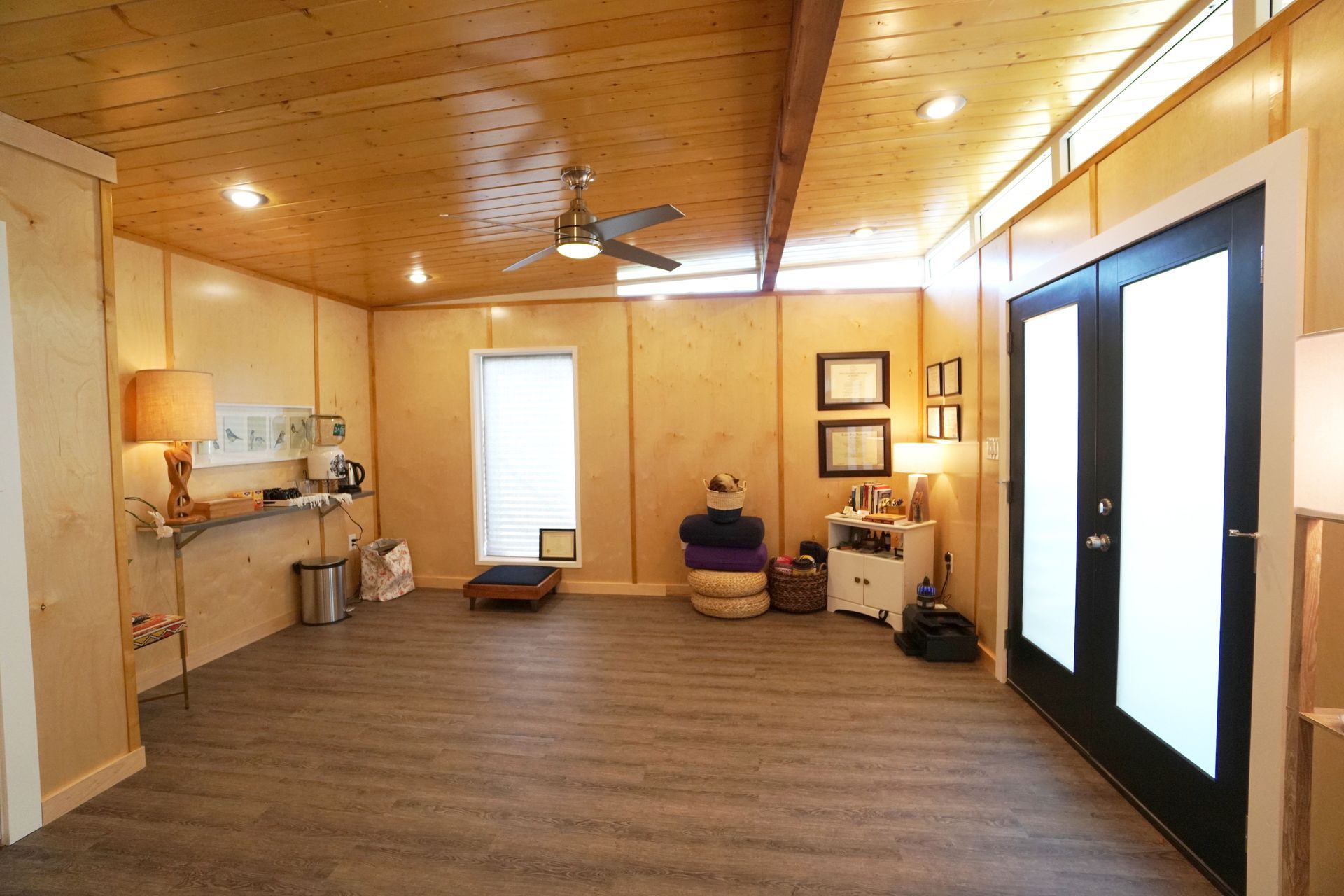 Bright interior room with wood paneling, French doors, and a ceiling fan.