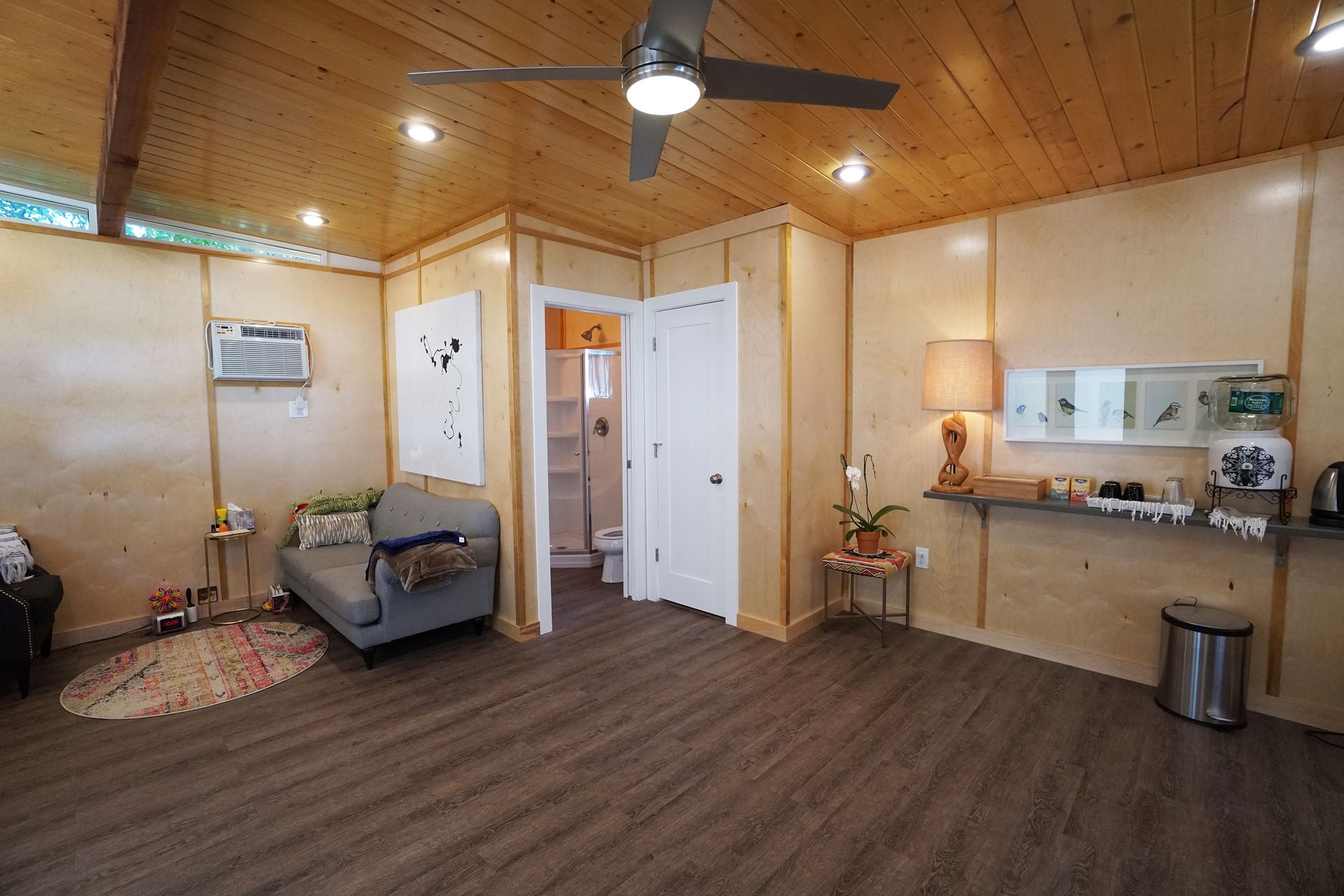 Interior view of a room with wood paneling, couch, and a small bathroom.