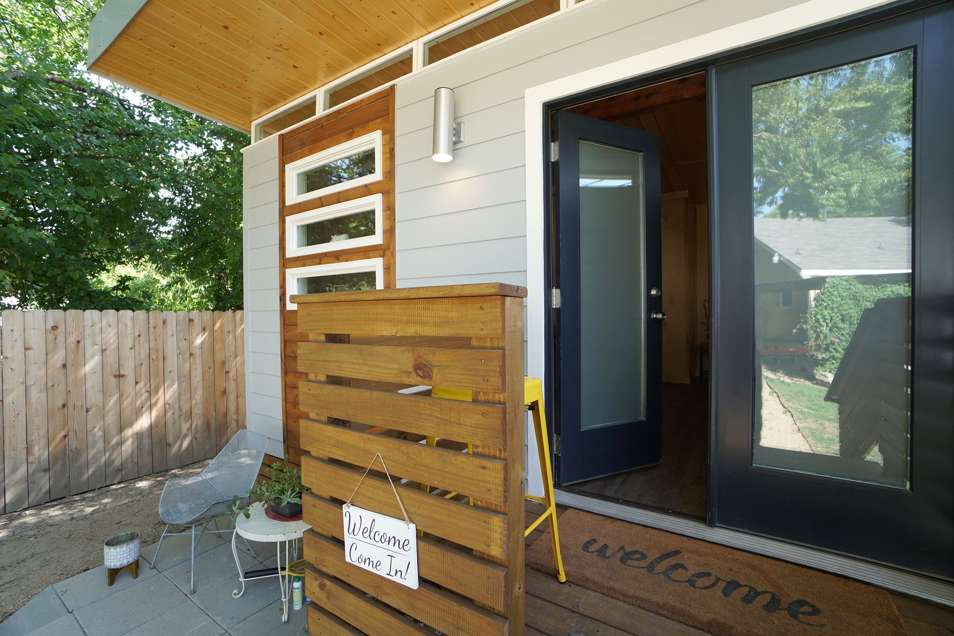 Exterior view of a modern building with a wooden fence and a double door entrance.
