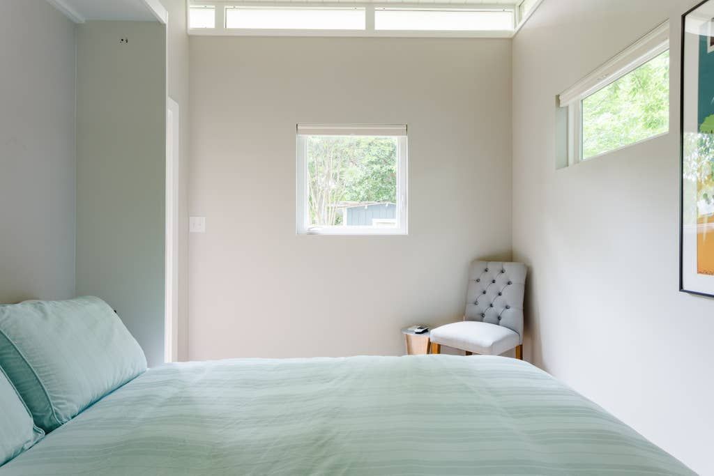 Bedroom with bed, chair, and window. Light green bedding, neutral walls.