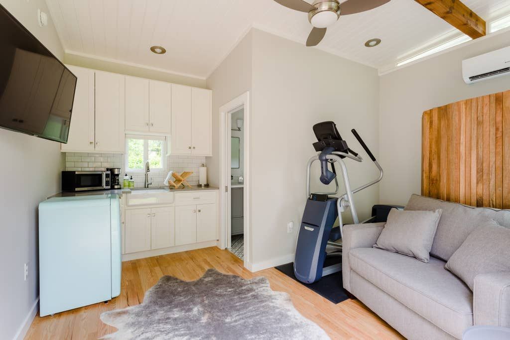 A bright room with a kitchen area, a sofa, and exercise equipment.