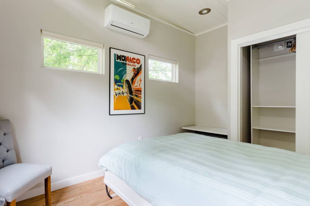Bedroom with a bed, closet, chair, framed poster, and air conditioning unit.