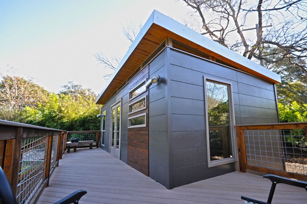 A small house with a deck and chairs in front of it