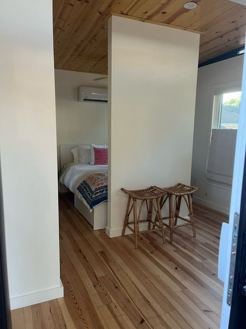Interior view of a bedroom with a white wall divider and wooden floor and ceiling.
