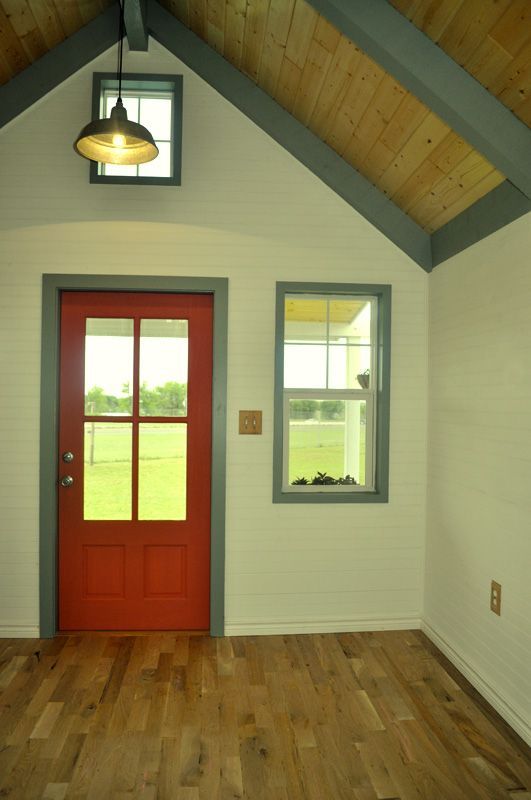 An empty room with a red door and two windows