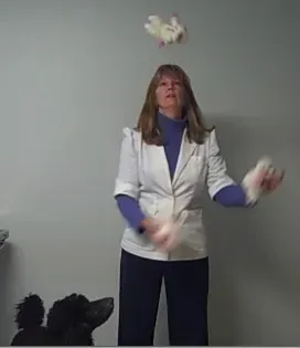 A woman in a white jacket is throwing a stuffed animal in the air.