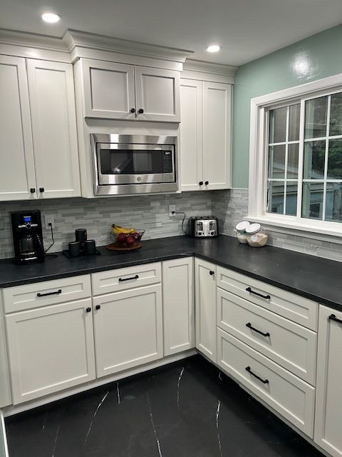 A Kitchen with White Cabinets and Black Counter Tops.
