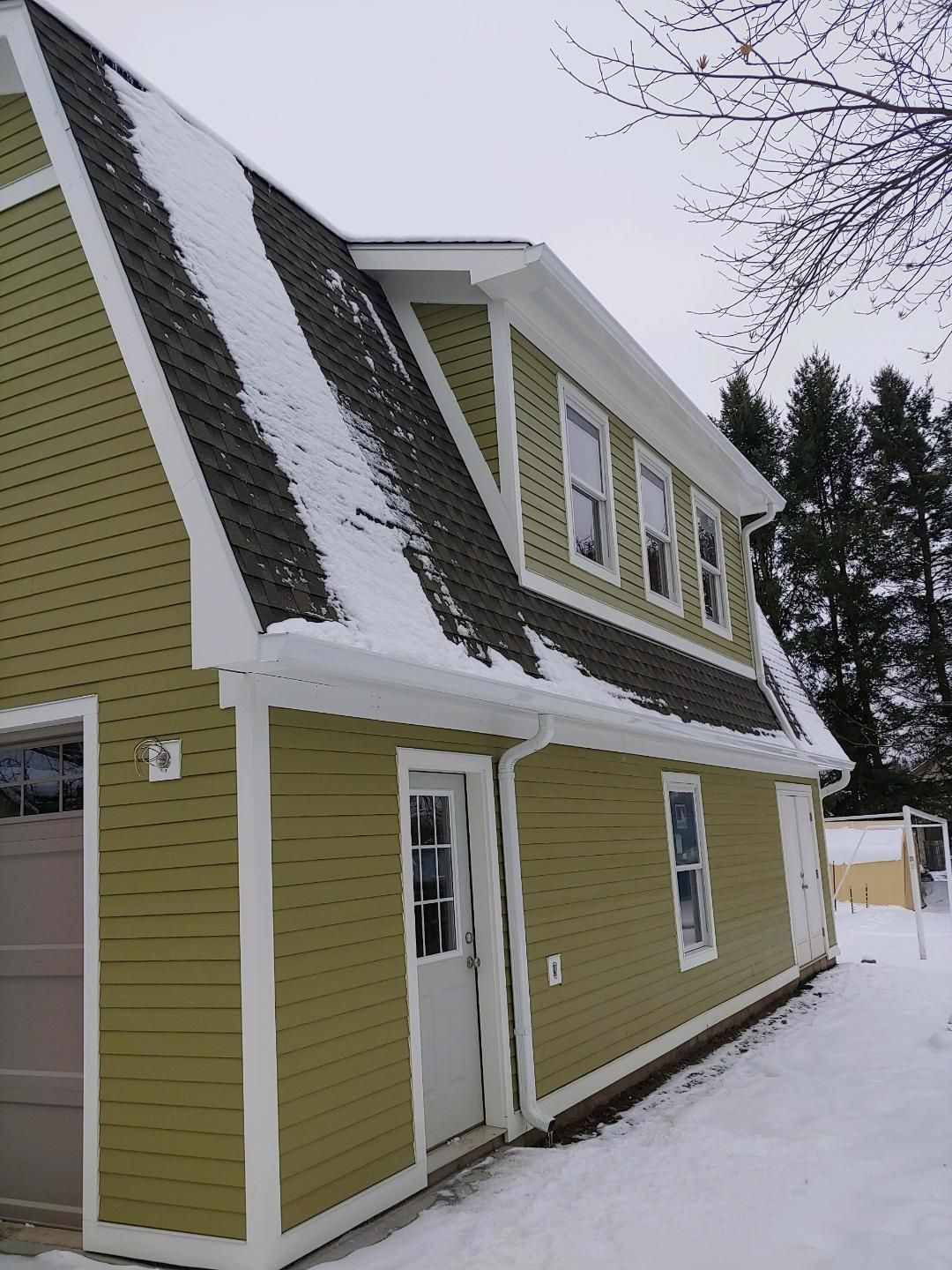 A house with snow on the roof and a garage