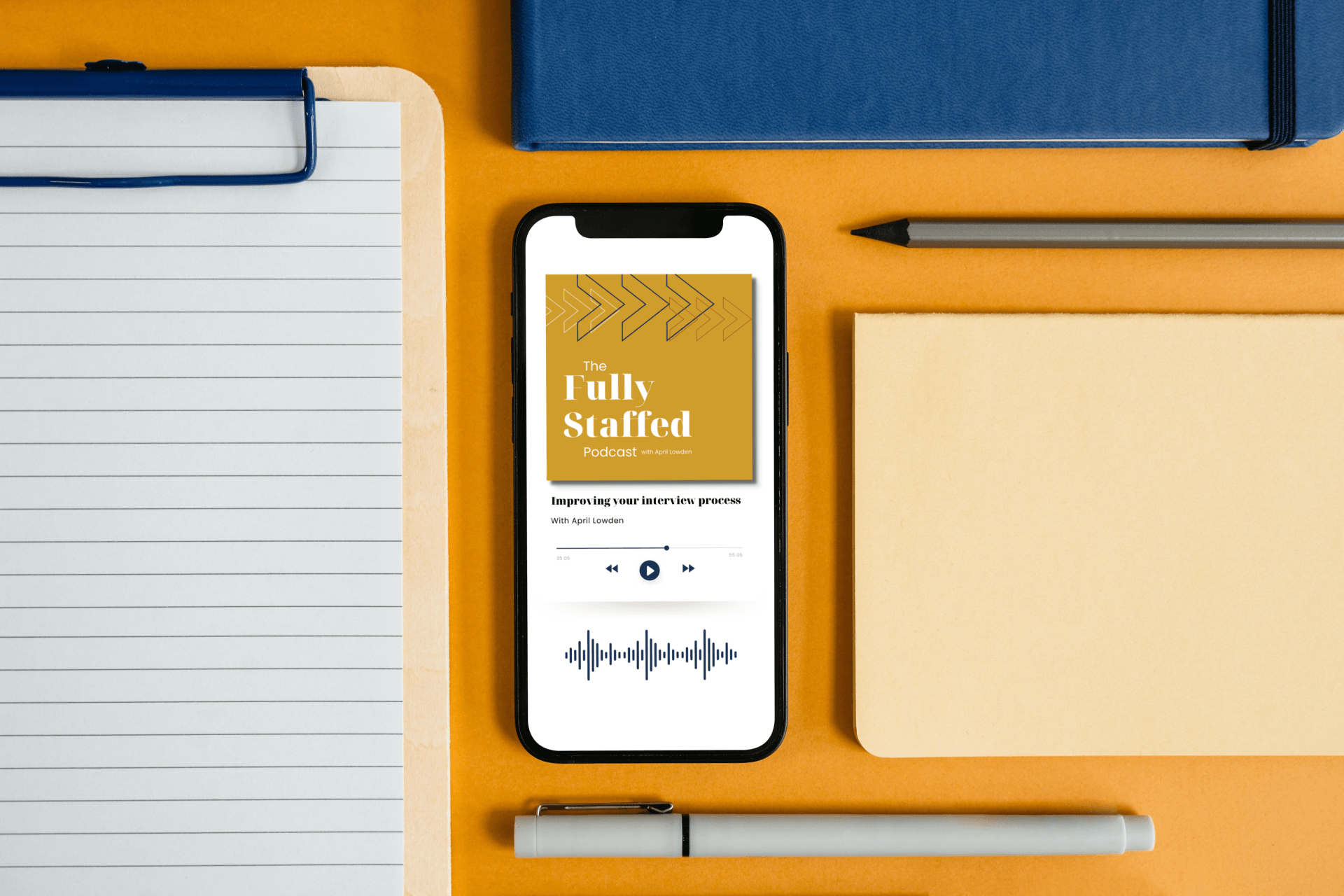blue and gold flatlay of office supplies surrounding an iPhone showing the Fully Staffed podcast cover